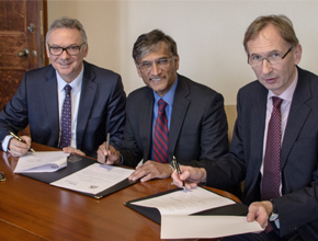 three professors sat at table with papers and smiling